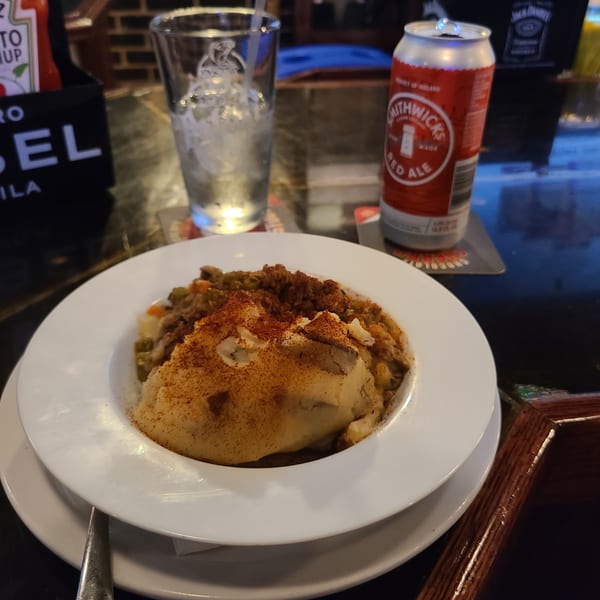 Shepherd's pie with mashed potato topping, a glass of water, and a can of Smithwick's Red Ale.